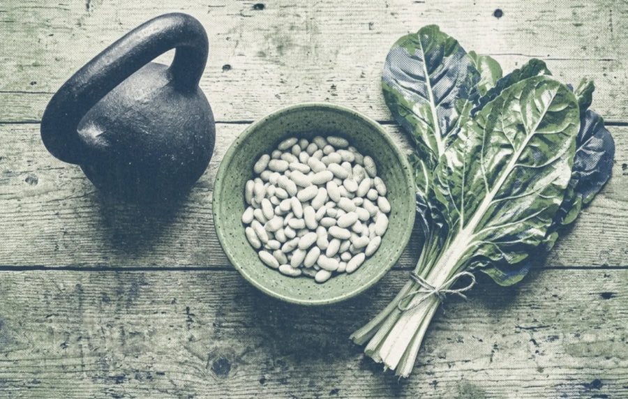 Two colour print of a kettlebell, a bowl of white beans and a bunch of chard on a wooden table